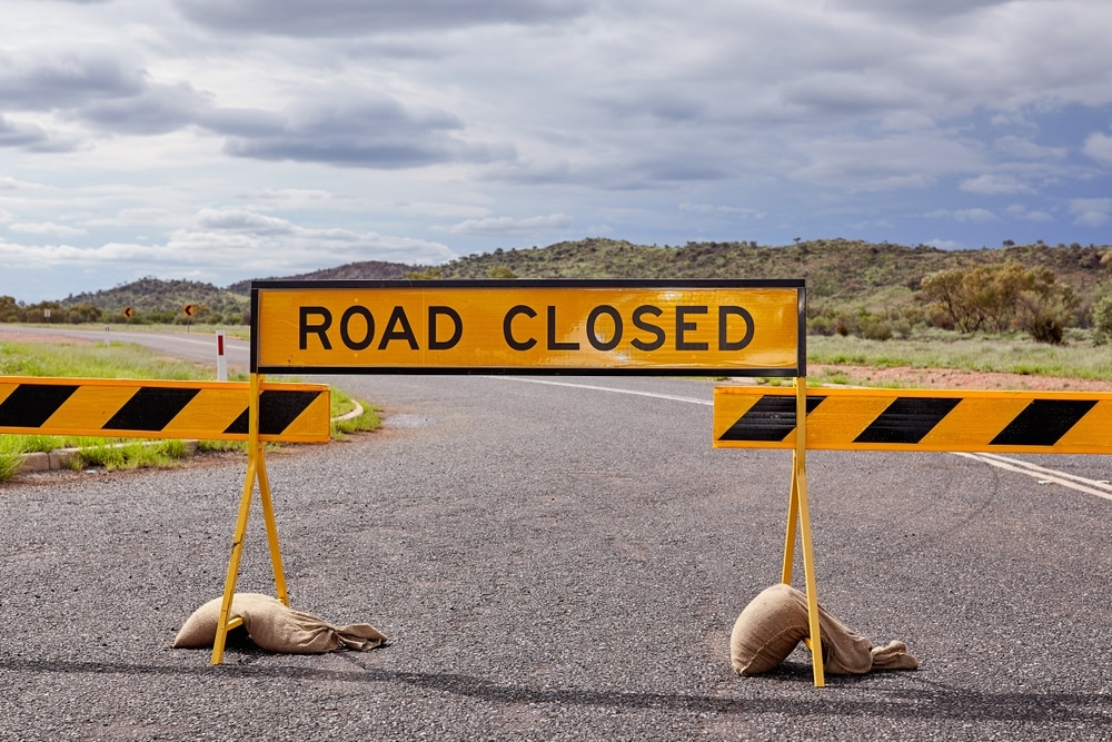 Road closed sign and barricades across a regional road