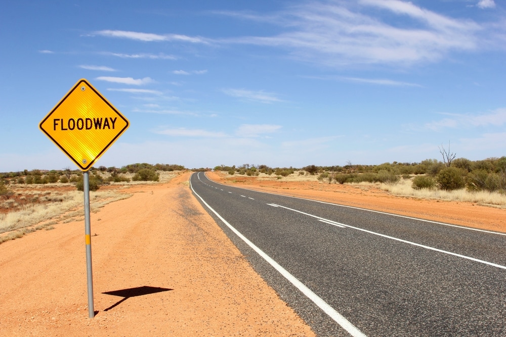 Floodway warning sign beside a line-marked regional road